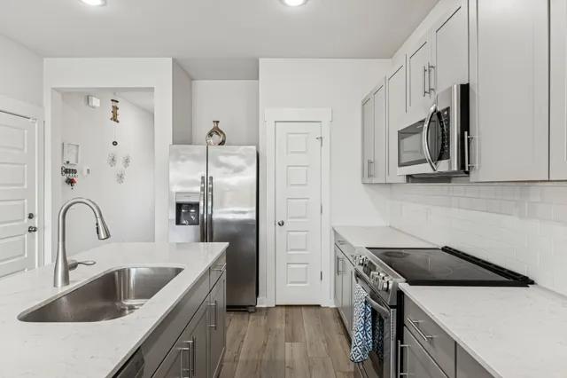 a kitchen with stainless steel appliances granite countertop a sink stove and refrigerator