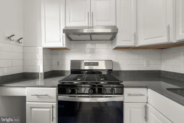 a kitchen with stainless steel appliances granite countertop a stove a sink and white cabinets