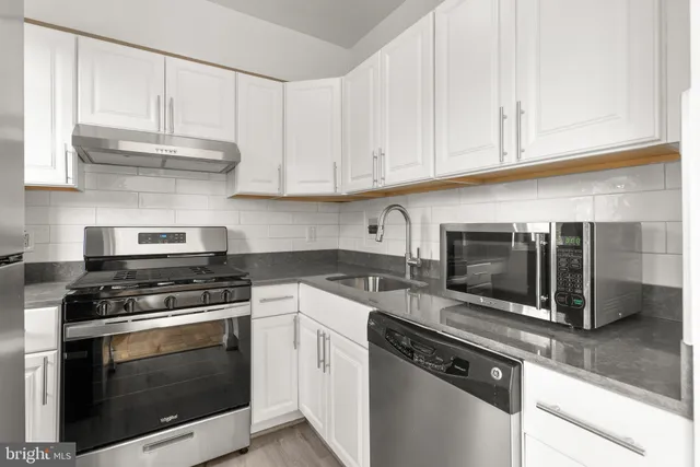 a kitchen with granite countertop white cabinets and black appliances