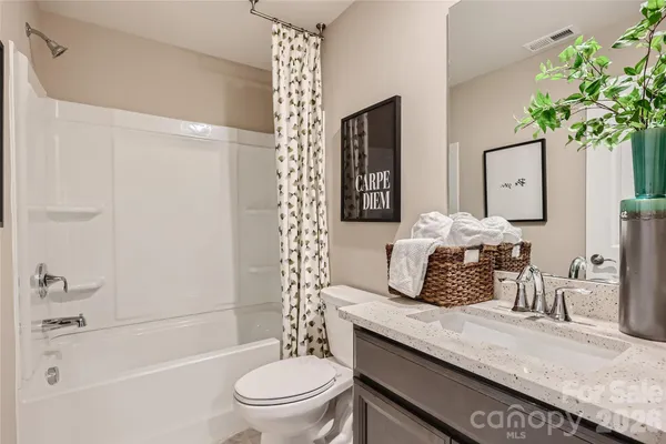 a bathroom with a granite countertop sink a toilet a mirror a vanity and shower