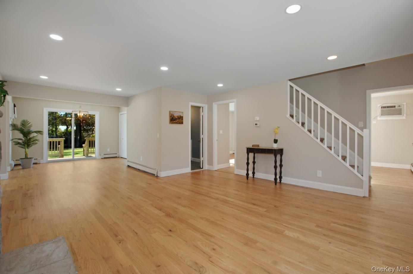 225 Lyman Road East Patchogue, NY 11772 - Photo 3 of 18 Unfurnished living room with recessed lighting, light wood-style floors, stairway, a baseboard heating unit, and a wall mounted AC