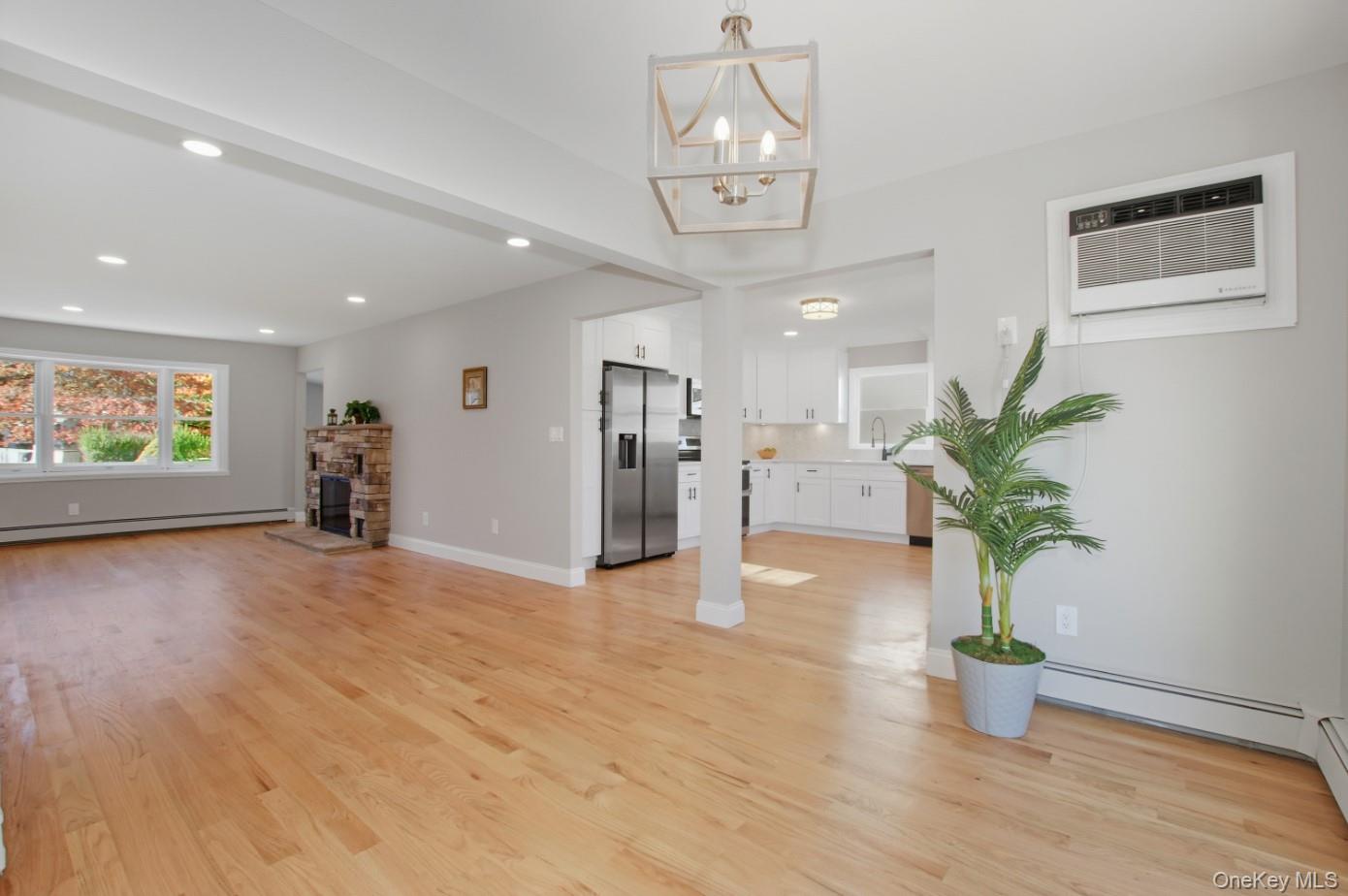 225 Lyman Road East Patchogue, NY 11772 - Photo 4 of 18 Unfurnished living room with light wood-style floors, recessed lighting, a wall mounted air conditioner, a fireplace, and a baseboard radiator
