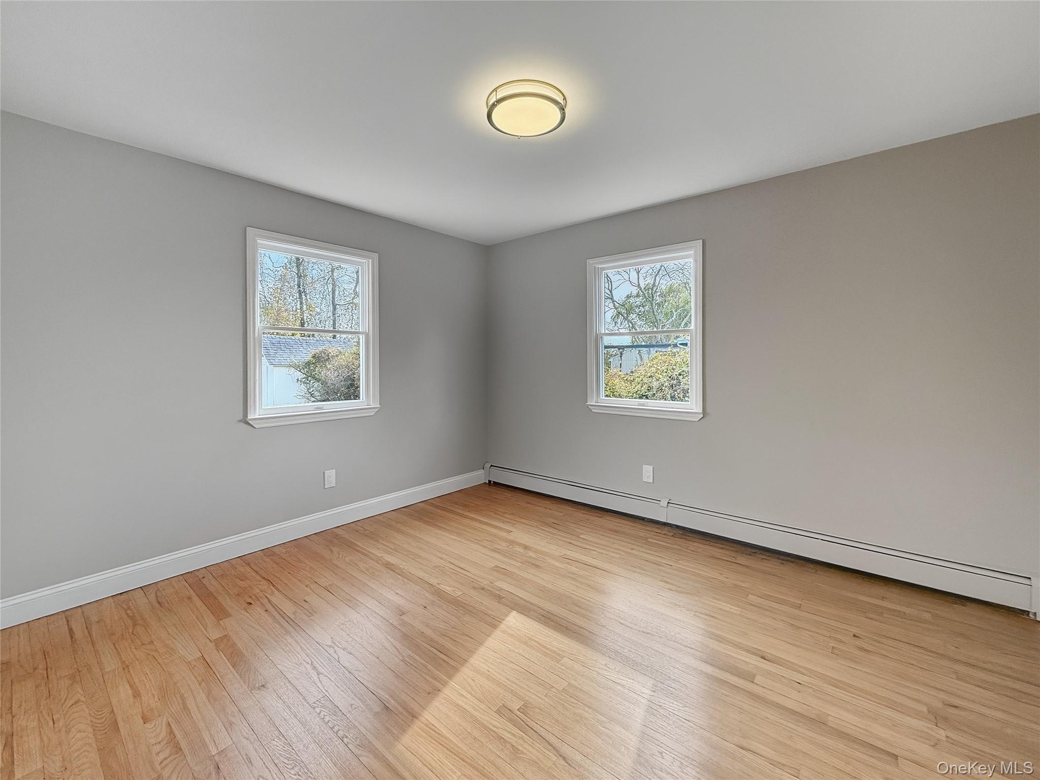 225 Lyman Road East Patchogue, NY 11772 - Photo 9 of 18 1st floor Bedroom featuring baseboard heating, healthy amount of natural light, and light wood finished floors