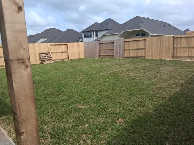 a view of a yard with wooden fence