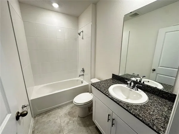 a bathroom with a granite countertop sink a mirror and a bathtub