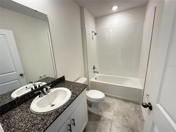 a bathroom with a granite countertop sink toilet mirror and shower
