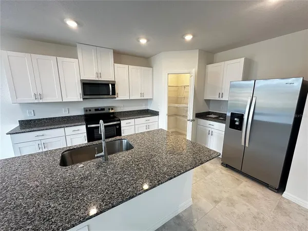 a kitchen with stainless steel appliances granite countertop a sink a stove and a refrigerator