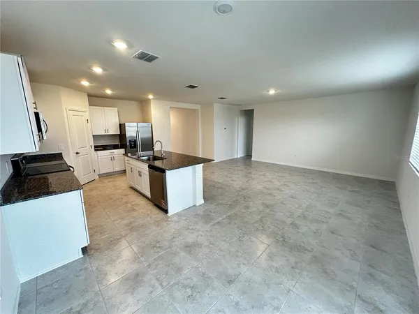 a view of a kitchen with kitchen island white cabinets and stainless steel appliances