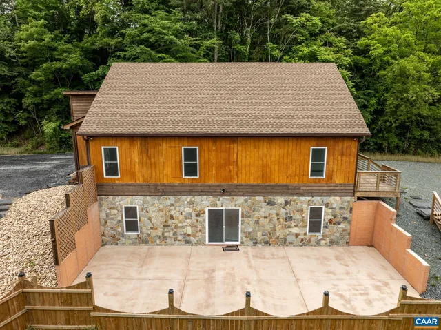 an aerial view of a house with swimming pool and trees in the background