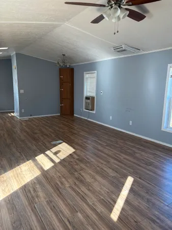 a view of an empty room with wooden floor and a ceiling fan