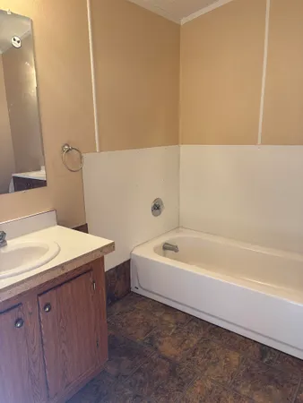 a spacious bathroom with a tub sink and mirror