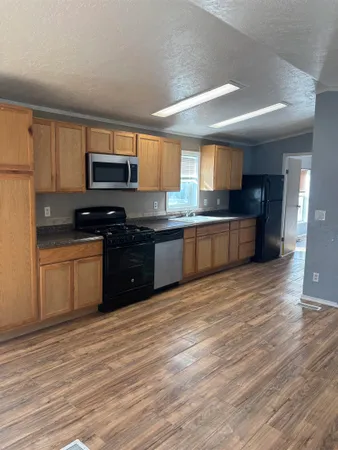 a large kitchen with stainless steel appliances granite countertop a stove a sink dishwasher and a microwave oven on the wooden floor