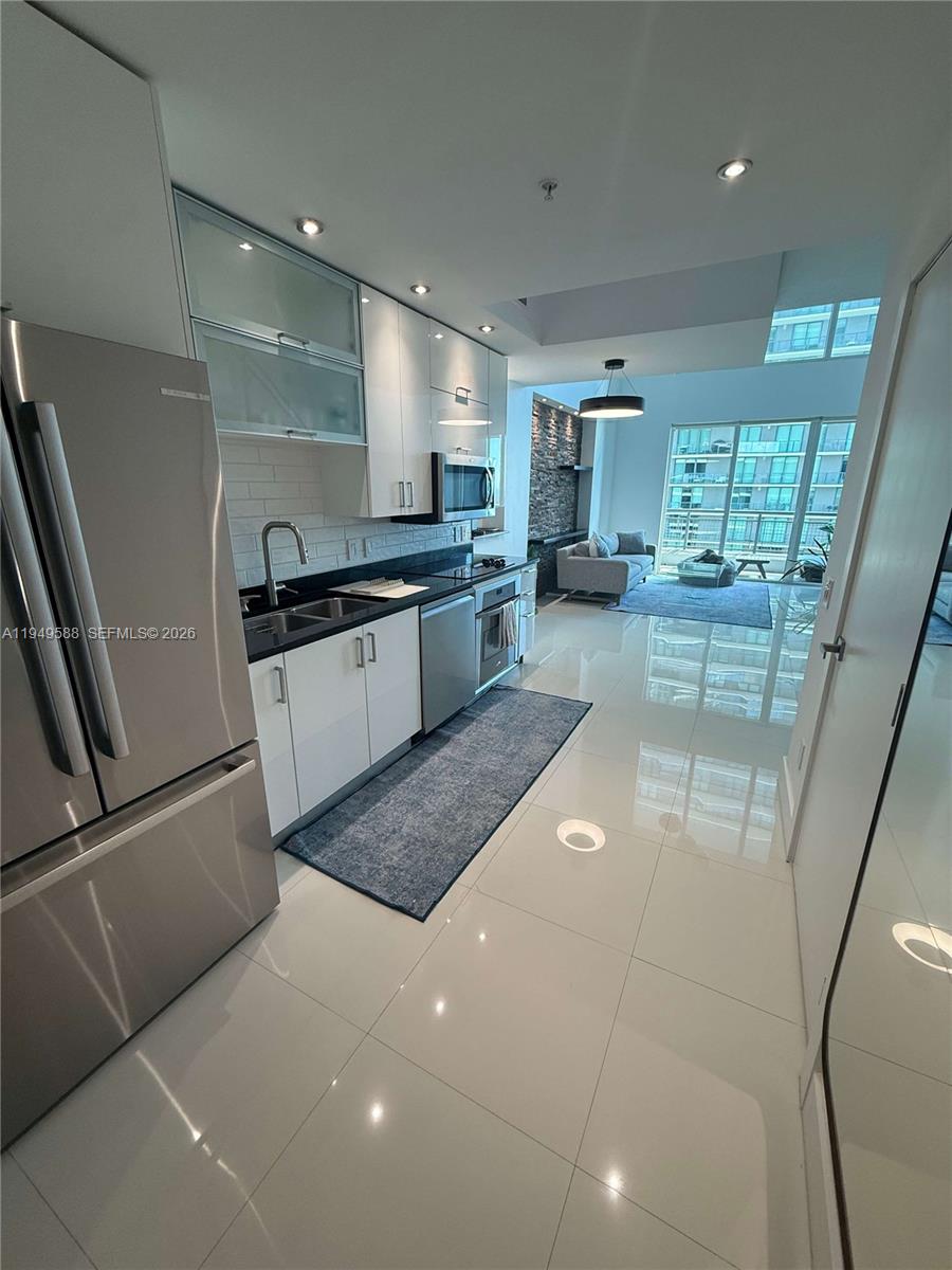60 Southwest 13th Street, Unit 3808 Miami, FL 33130 - Photo 2 of 38 a large kitchen with stainless steel appliances a large counter top a stove a chimney a sink and cabinets