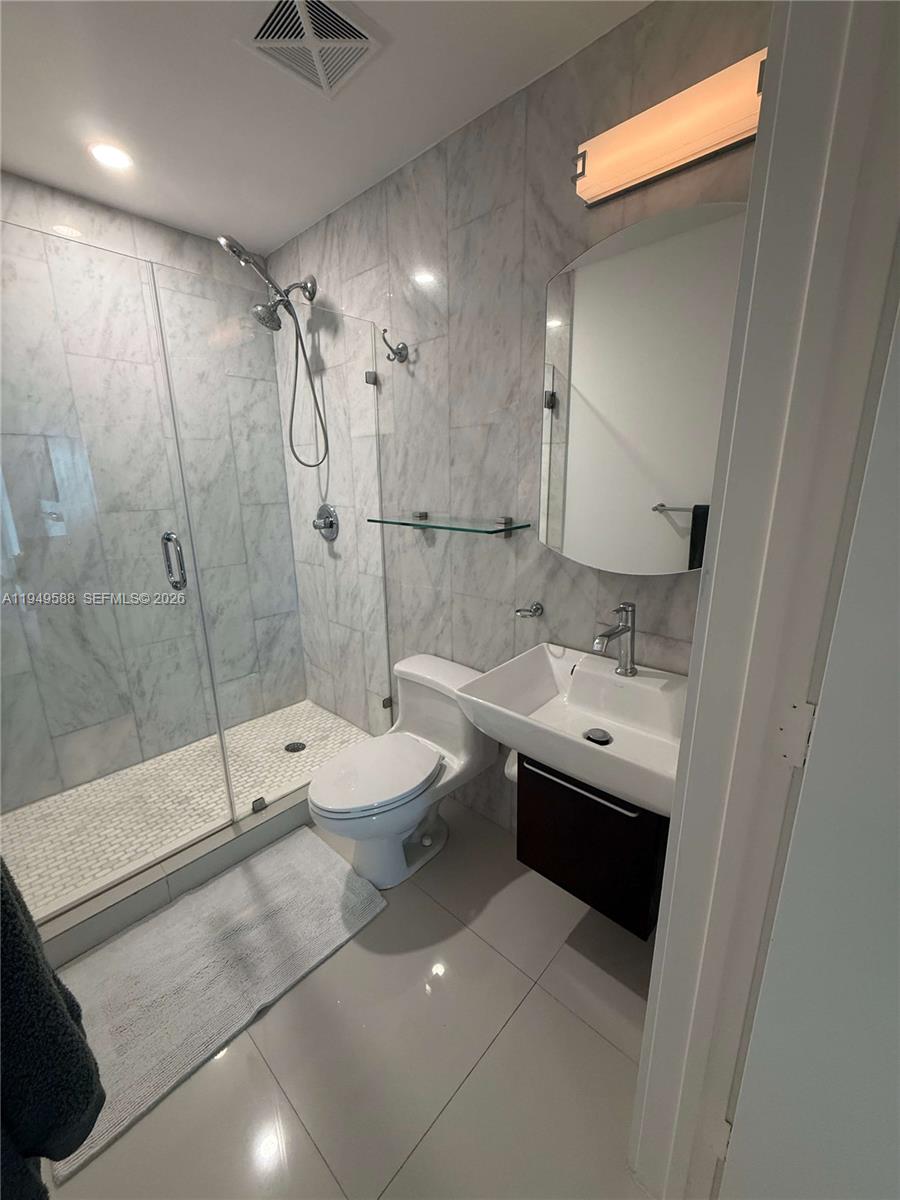 60 Southwest 13th Street, Unit 3808 Miami, FL 33130 - Photo 27 of 38 a bathroom with a double vanity sink toilet mirror and shower