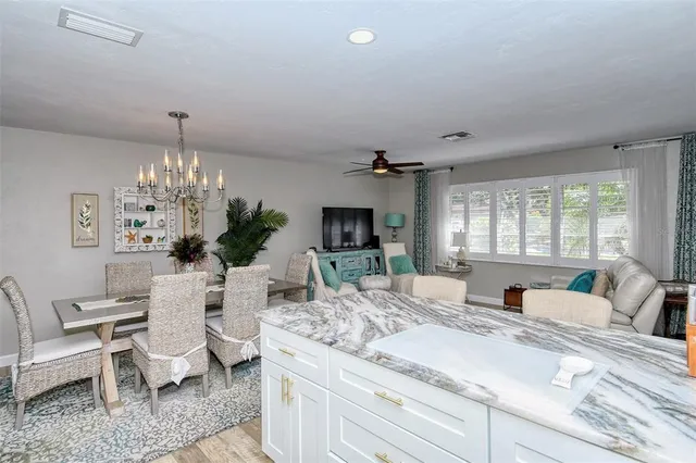 a very nice looking dining room with kitchen island stainless steel appliances furniture a chandelier and a view of kitchen