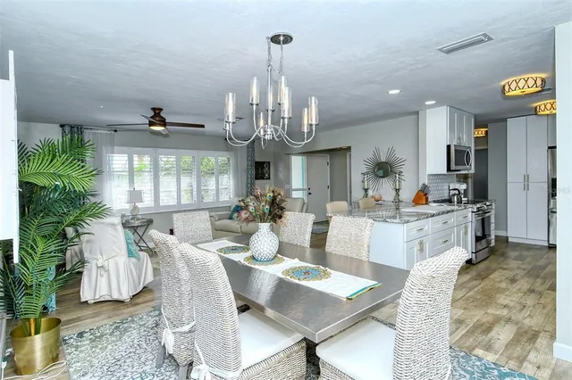 a kitchen with stainless steel appliances granite countertop a sink a stove a refrigerator cabinets and a wooden floor