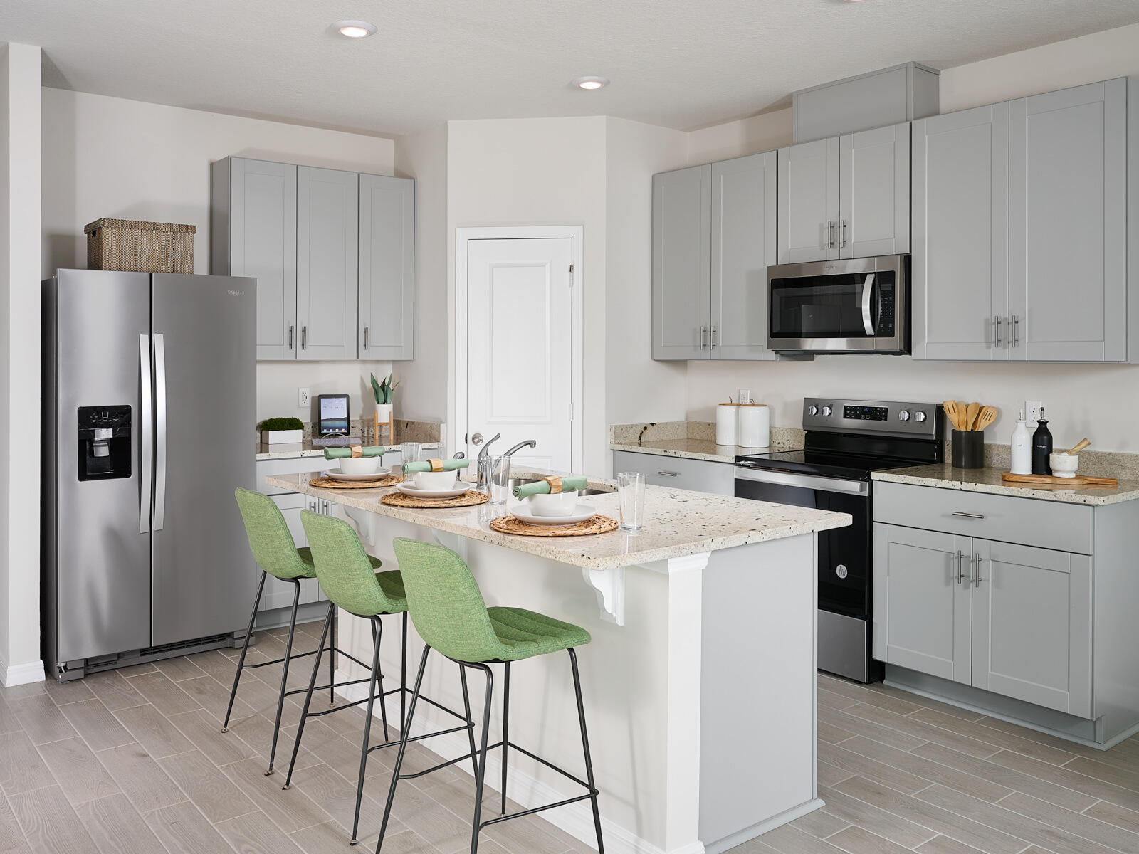 5672 Southeast Edgewater Circle Stuart, FL 34997 - Photo 5 of 8 a kitchen with stainless steel appliances kitchen island granite countertop a sink a stove a refrigerator and white cabinets with wooden floor