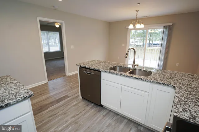 a kitchen with granite countertop a sink cabinets and wooden floor