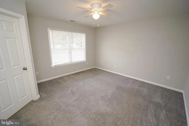 an empty room with a window and a fan