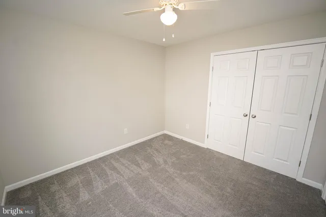 an empty room with a ceiling fan and a window