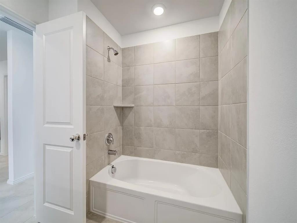 352 Sun Bluff Road Fort Worth, TX 76052 - Photo 29 of 33 White tub-shower combination featuring light-toned tile surround with integrated shelf, polished chrome fixtures, and recessed ceiling lighting
