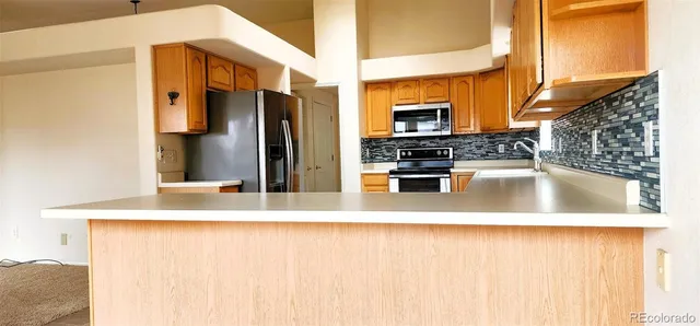 a view of a kitchen with kitchen island a sink stainless steel appliances and cabinets