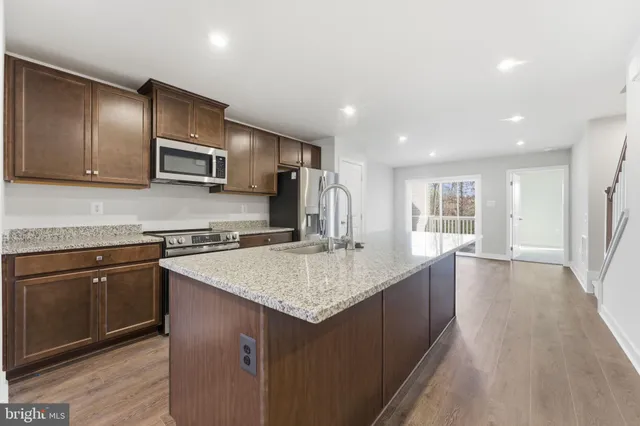 a kitchen with stainless steel appliances granite countertop a refrigerator a stove and a sink