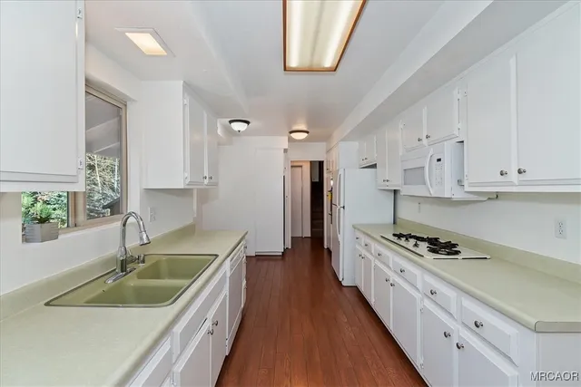 a kitchen with granite countertop a sink a stove and cabinets