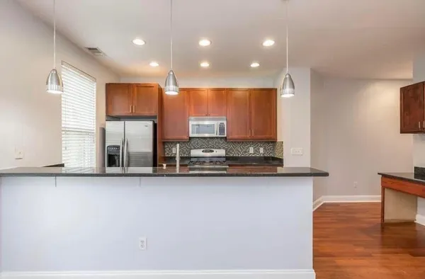 a view of a kitchen with stainless steel appliances granite countertop a stove a sink and a microwave