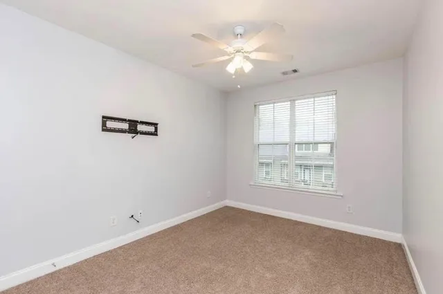 an empty room with windows and chandelier fan