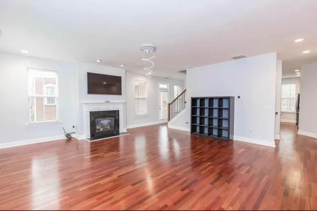 a view of an empty room with wooden floor and a fireplace