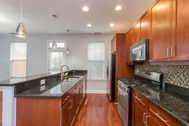 a kitchen with granite countertop kitchen island stainless steel appliances a stove sink and microwave