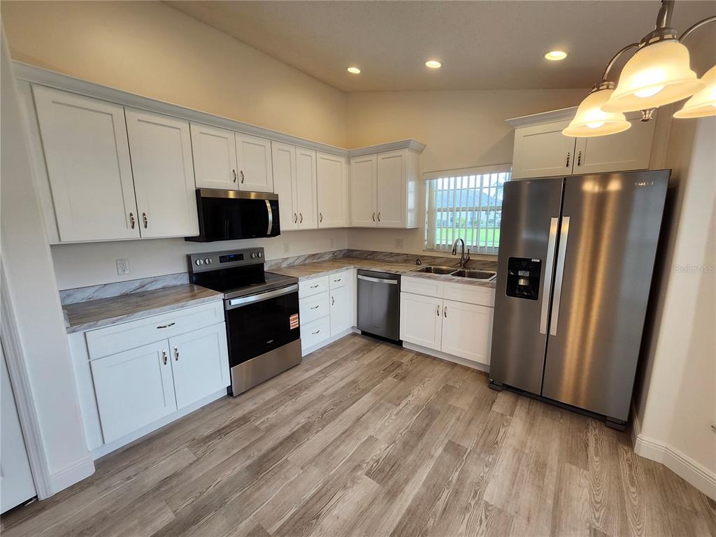 4694 Prairie Point Boulevard Kissimmee, FL 34746 - Photo 3 of 23 a kitchen with white cabinets and stainless steel appliances