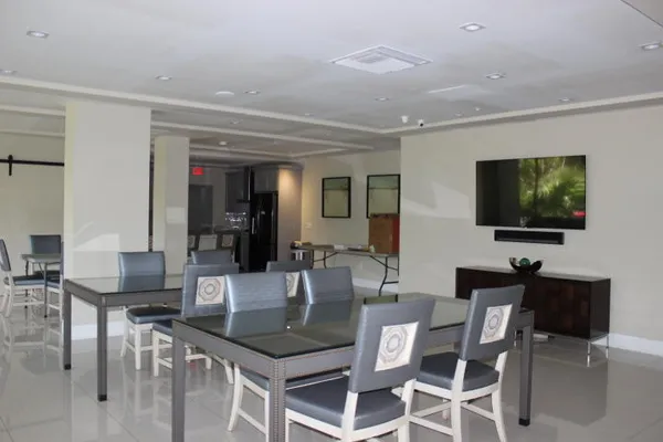 a dining hall with stainless steel appliances kitchen island granite countertop a table and chairs