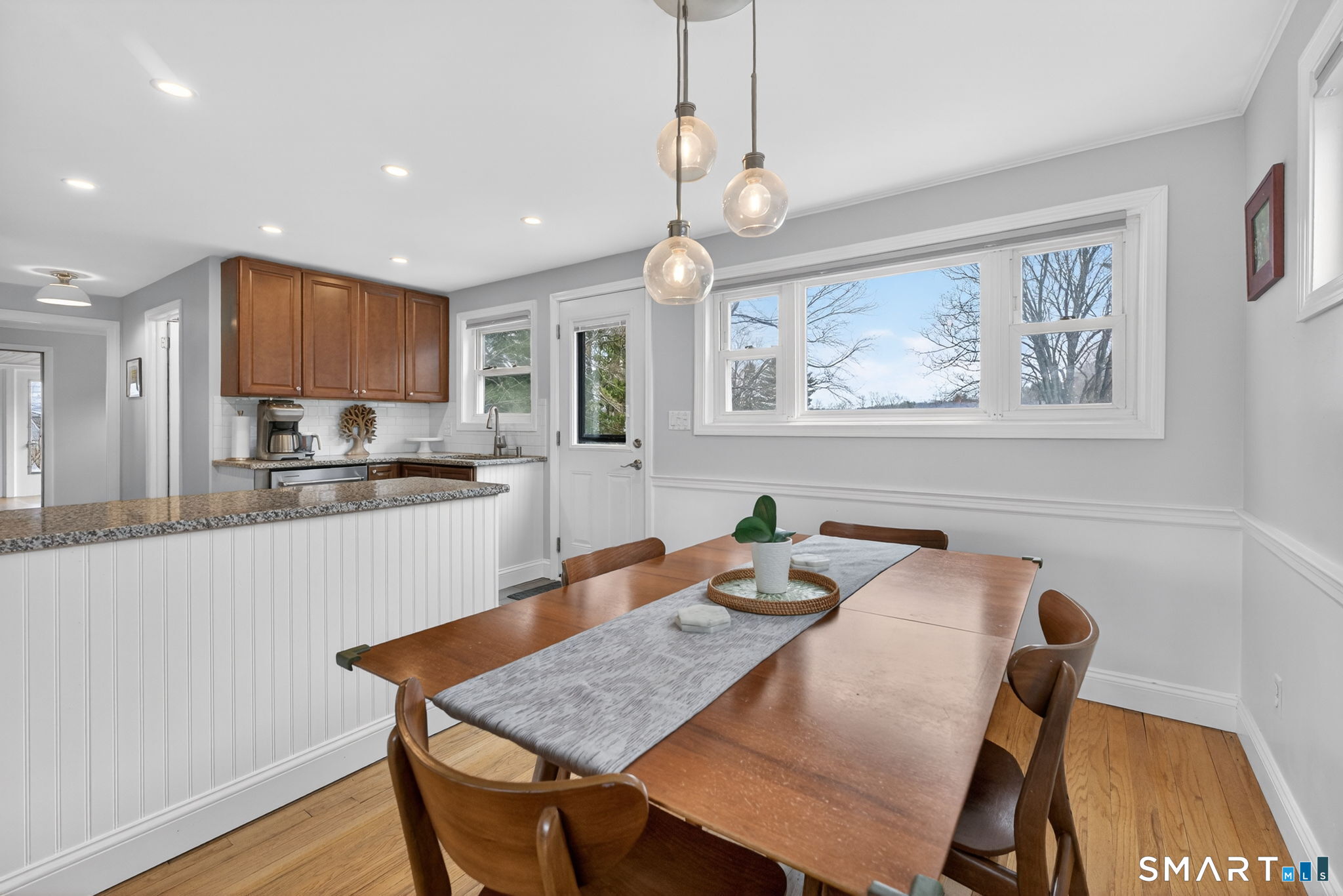 12 Lewis Street Simsbury, CT 06081 - Photo 7 of 35 a kitchen with stainless steel appliances granite countertop a stove a refrigerator a sink a dining table and chairs with wooden floor