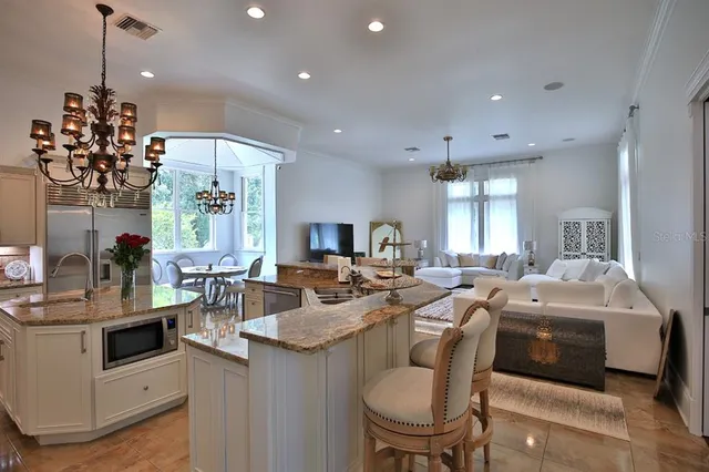 a very nice looking dining room with stainless steel appliances furniture a chandelier a rug and a window