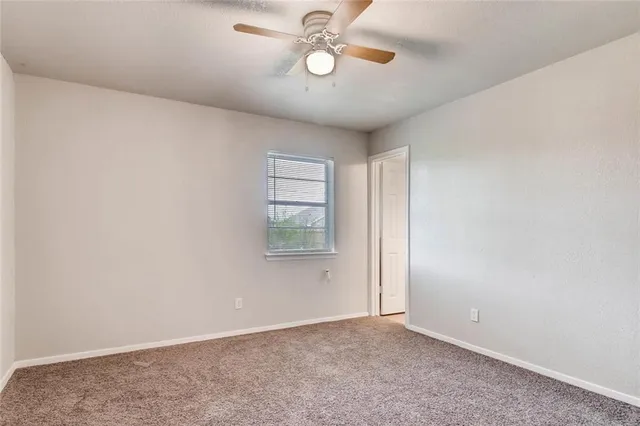an empty room with windows and ceiling fan
