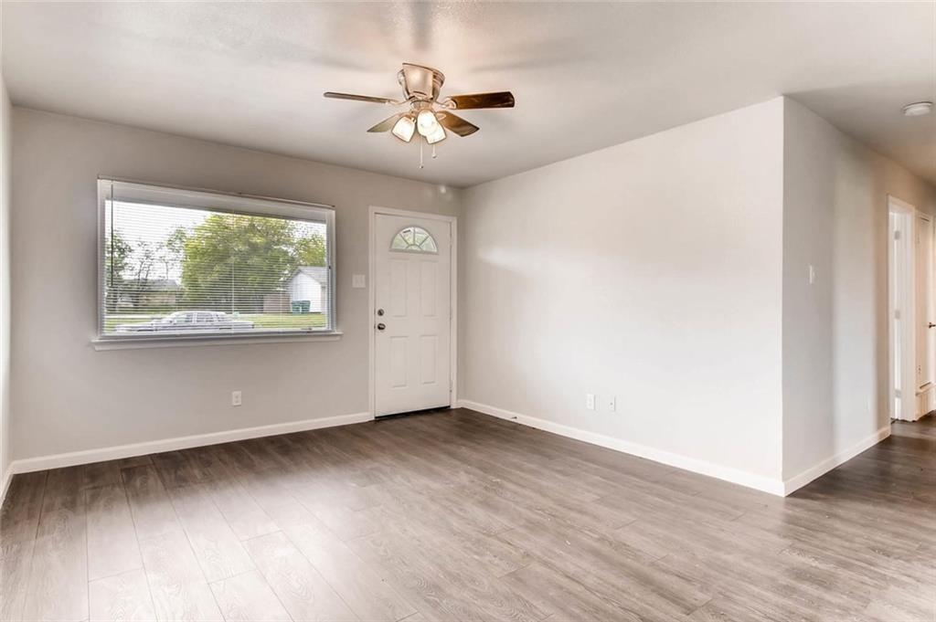 4903 Church Street Greenville, TX 75401 - Photo 6 of 10 an empty room with wooden floor chandelier fan and windows