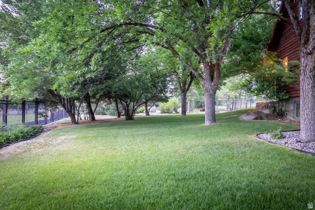 435 Canyon Road Millville, UT 84326 - Photo 60 of 113 Expansive lawn area featuring mature trees, a privacy fence, and a rock bed perimeter