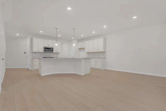 a view of kitchen with kitchen island a sink wooden floor white stainless steel appliances and cabinets