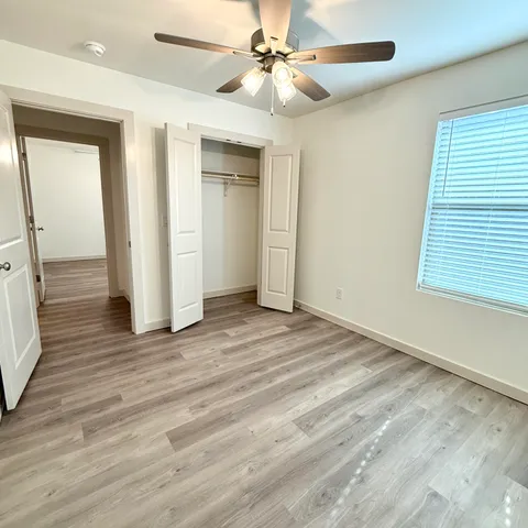 an empty room with wooden floor closet and windows