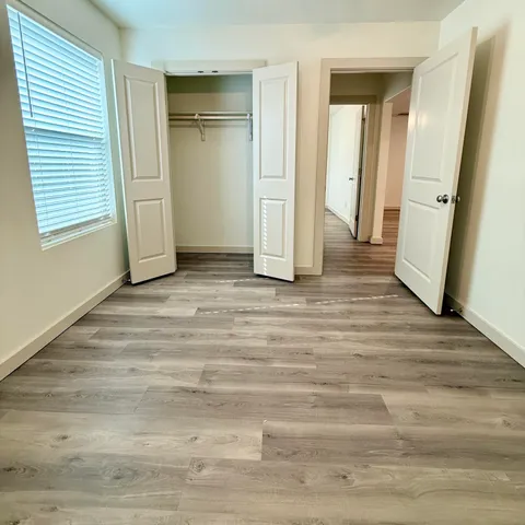 a view of an empty room with wooden floor and a window