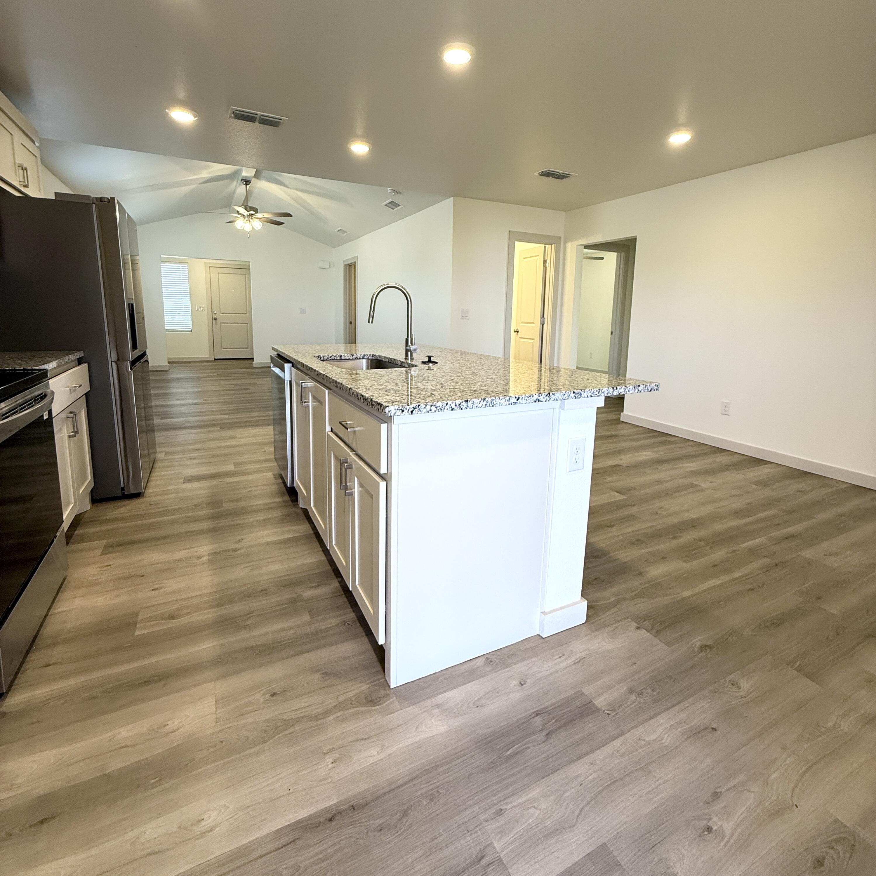 7702 Elm Avenue Lubbock, TX 79404 - Photo 4 of 16 a large kitchen with stainless steel appliances a large center island and a wooden floor