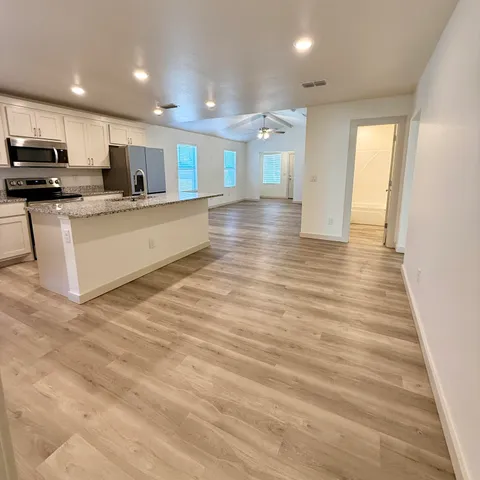 a large kitchen with stainless steel appliances granite countertop a large counter top and a stove with wooden floor