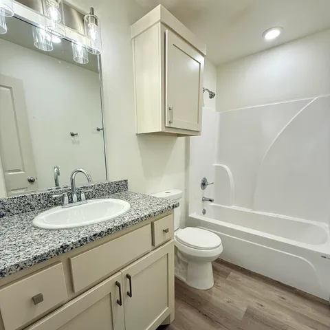 a bathroom with a granite countertop toilet a sink and a bathtub