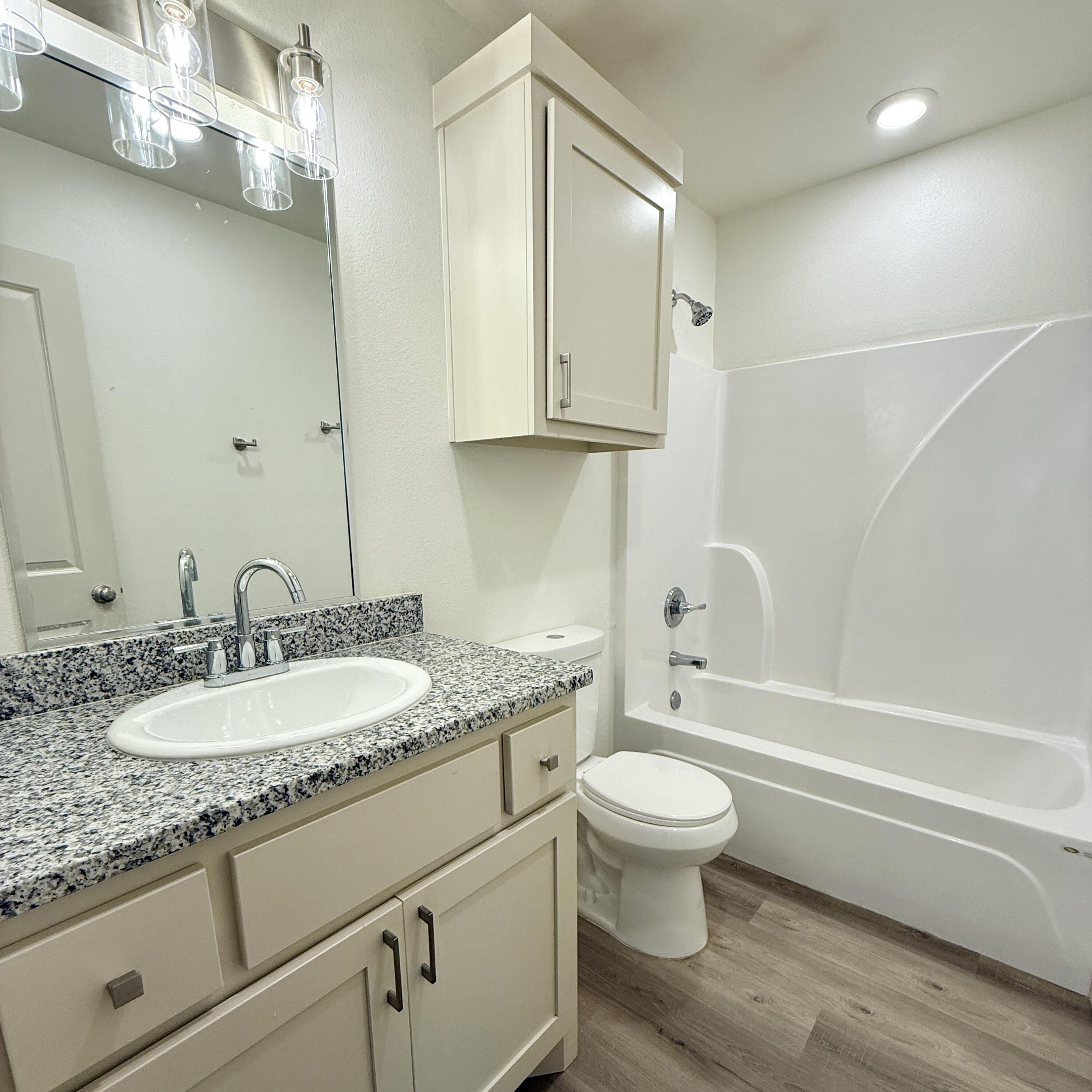 7702 Elm Avenue Lubbock, TX 79404 - Photo 10 of 16 a bathroom with a granite countertop toilet a sink and a bathtub