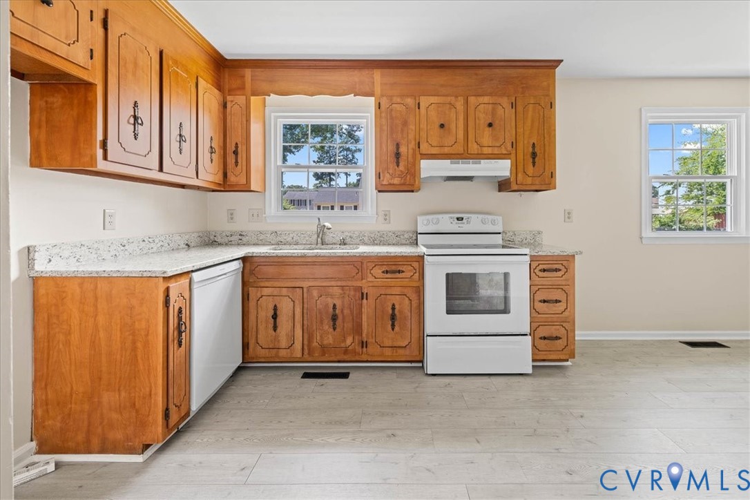 Kitchen featuring white appliances, light wood-sty