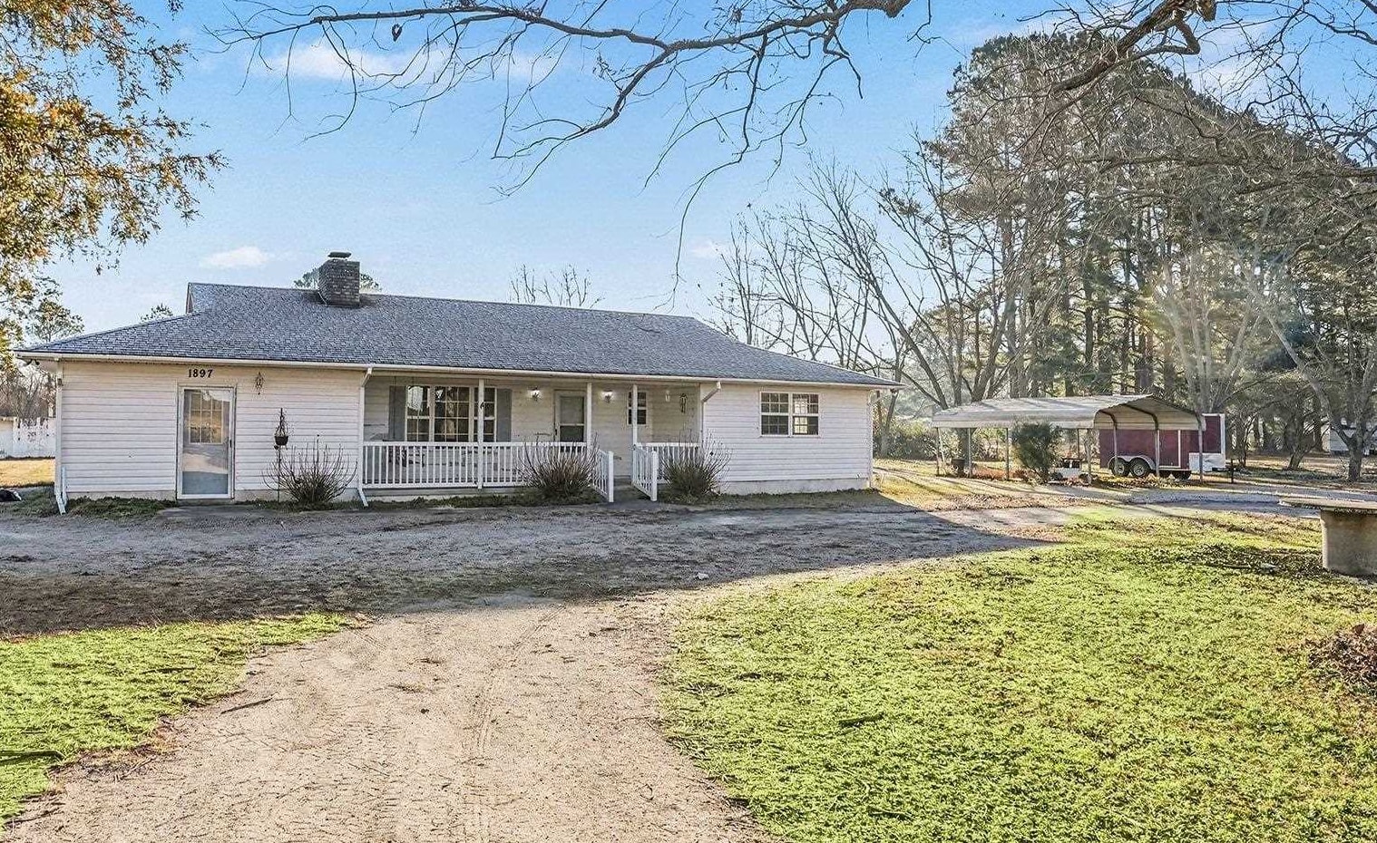 Single story home featuring a chimney, a porch, driveway, and a front yard