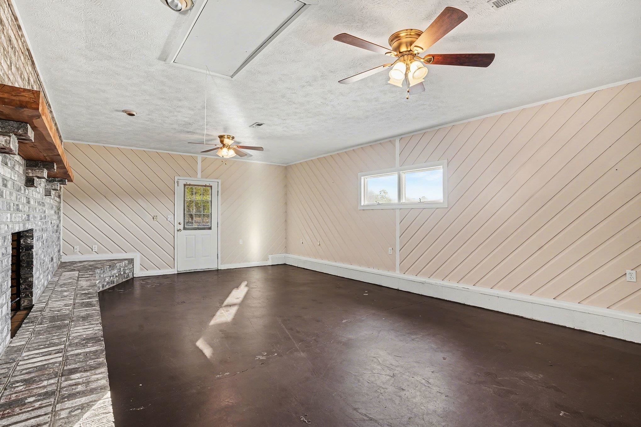1897 Heritage Road Loris, SC 29569 - Photo 5 of 32 Unfurnished living room with a ceiling fan, a textured ceiling, attic access, a brick fireplace, and concrete flooring