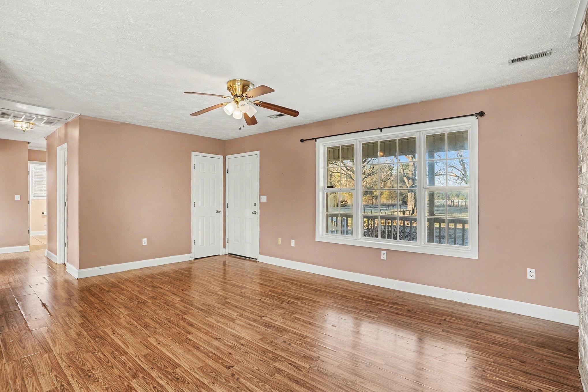 1897 Heritage Road Loris, SC 29569 - Photo 7 of 32 Empty room with light wood finished floors, a textured ceiling, and a ceiling fan
